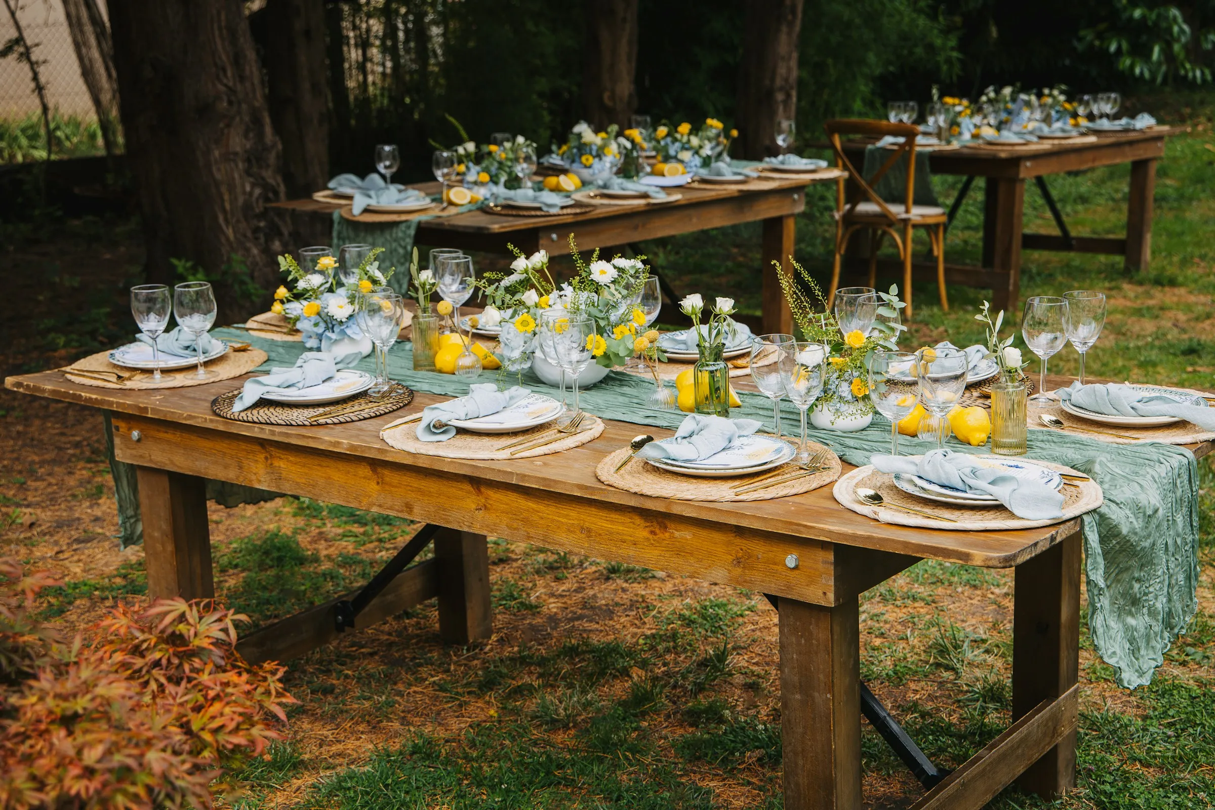 Flower-filled wedding tables beneath trees in a garden